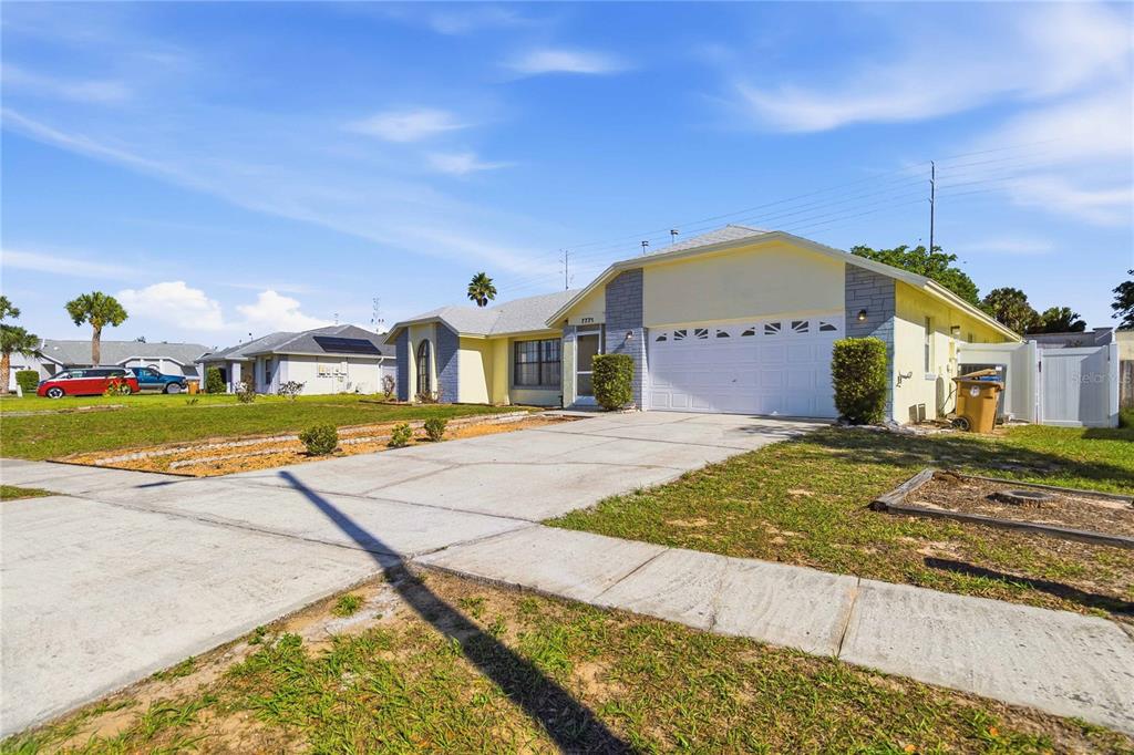 A single-story house with a yellow exterior, a two-car garage, and a concrete driveway — 7771 INDIAN RIDGE TRAIL N, KISSIMMEE, FL