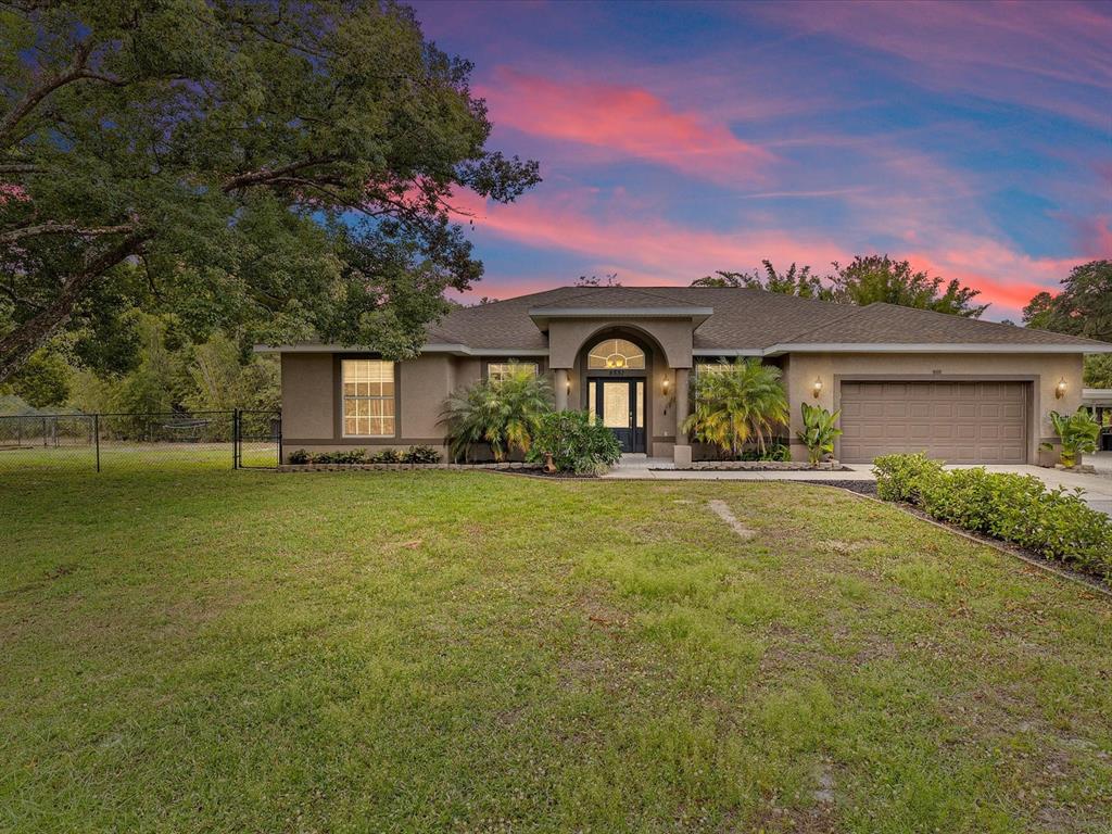 A single-story house with a brown exterior, a two-car garage, and a large front lawn — 8551 PRATT DRIVE, NEW PORT RICHEY, FL