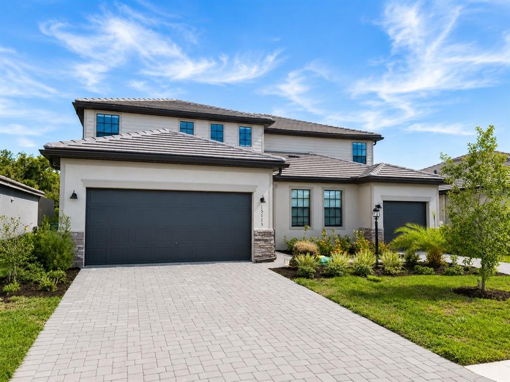A two-story suburban house features a paved driveway, two garage doors, and a tiled roof — 15115 SEA SALT WAY, BRADENTON, FL