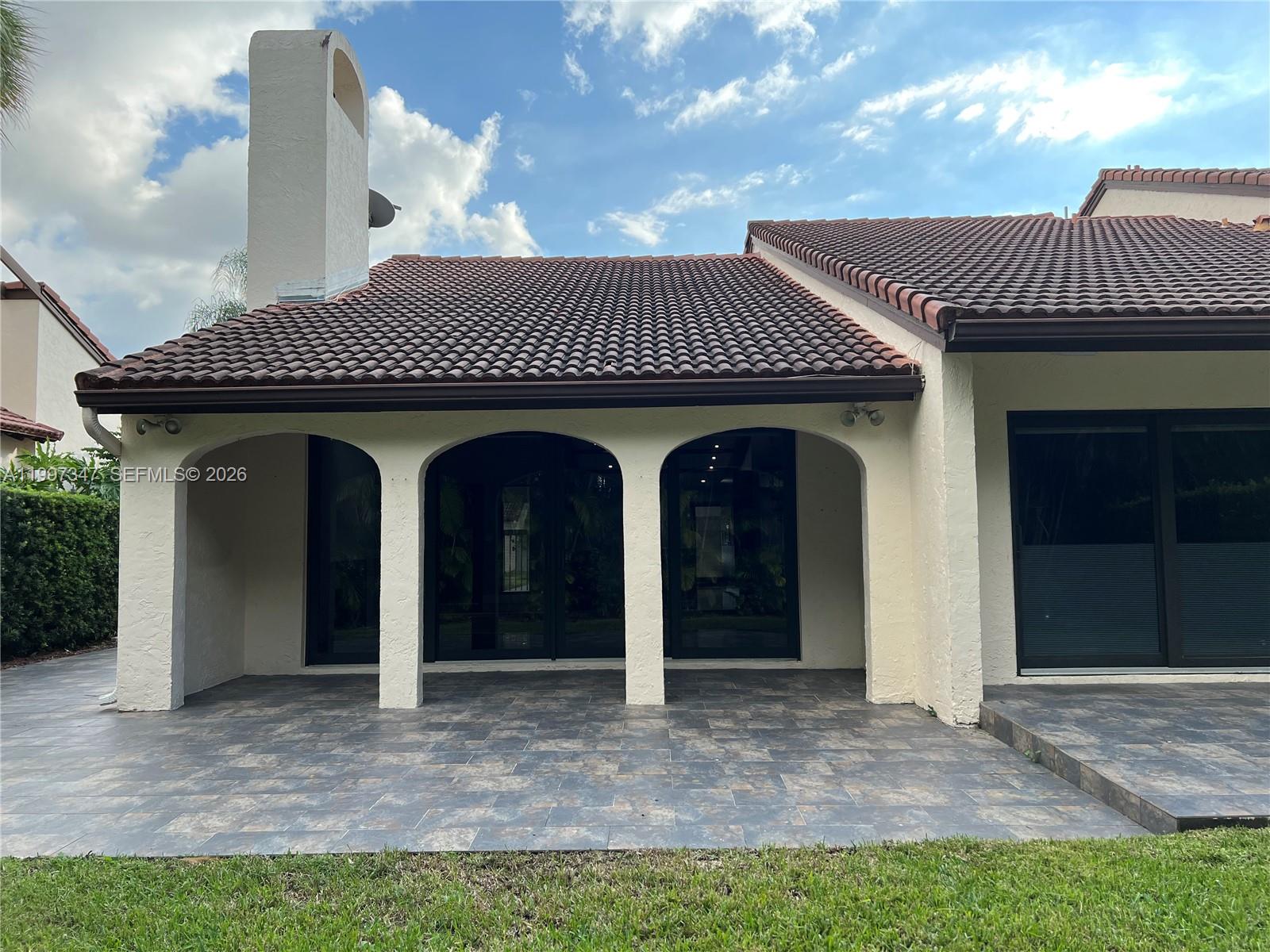 A living area with a sunken floor, glossy tiles, exposed wood beams, and a kitchen — 9331 NW 48th Doral Ter # 0, Doral FL 33178, DORAL, FL