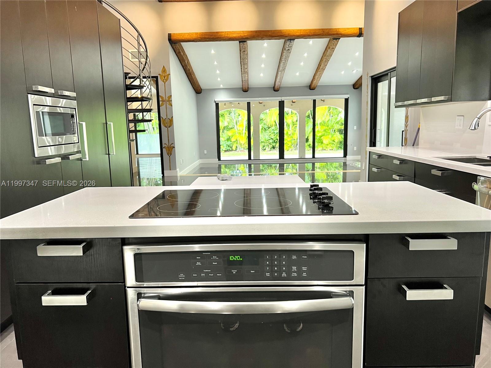 A spacious room features dark tile floors, exposed wooden ceiling beams, and a spiral staircase — 9331 NW 48th Doral Ter # 0, Doral FL 33178, DORAL, FL