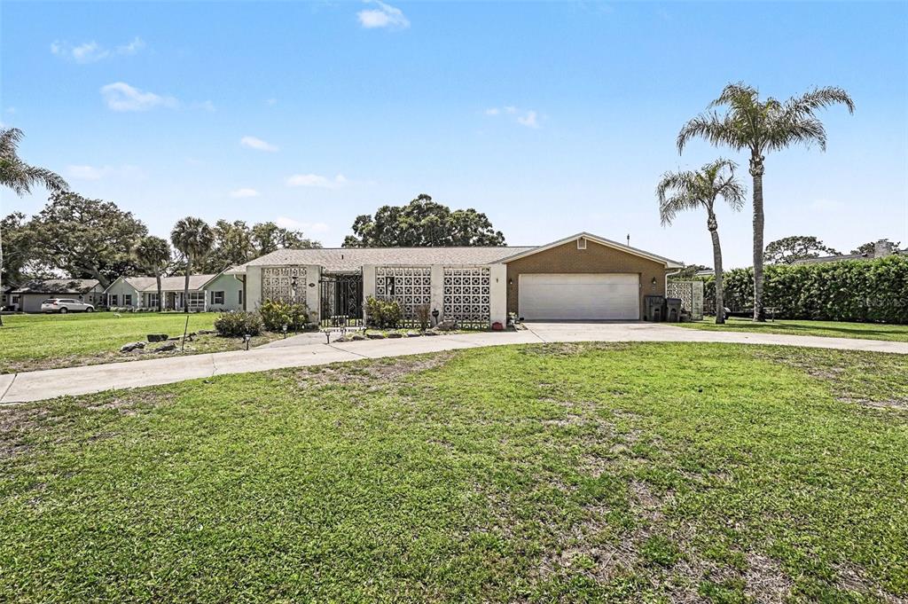 A single-story house with a brick garage, decorative concrete block walls, and palm trees — 3100 SAUNDERS PLACE, TITUSVILLE, FL