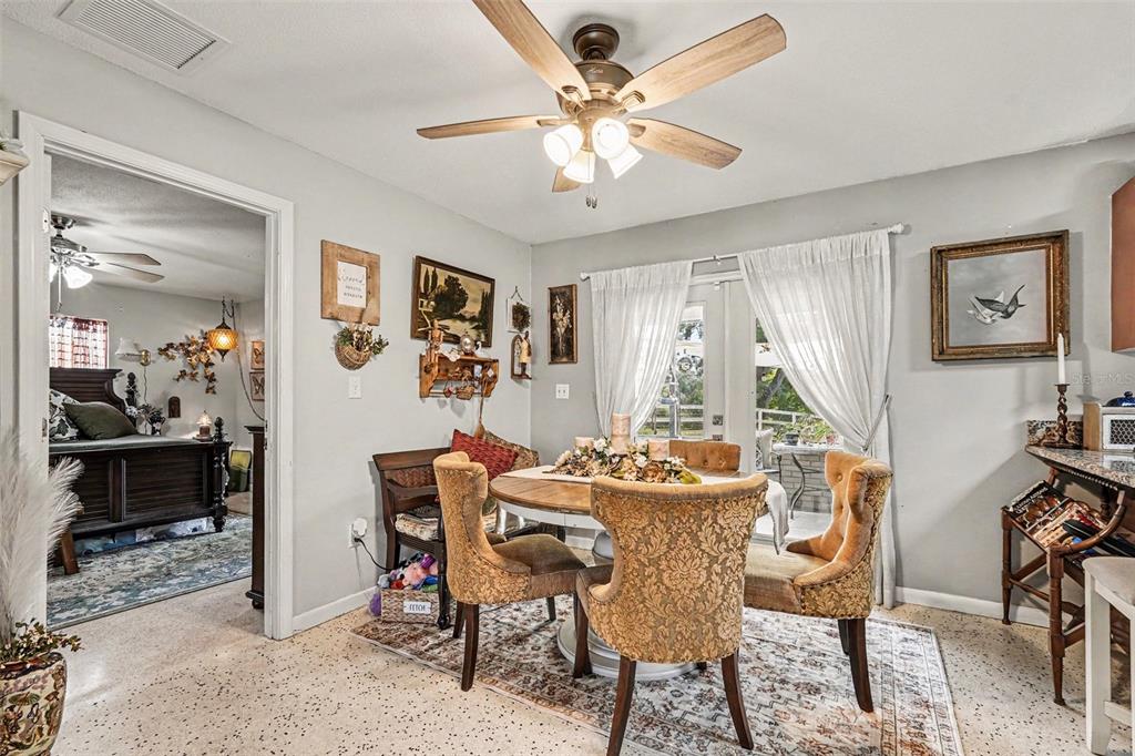 A dining area features a round table with upholstered chairs, a ceiling fan, and tile flooring — 3100 SAUNDERS PLACE, TITUSVILLE, FL