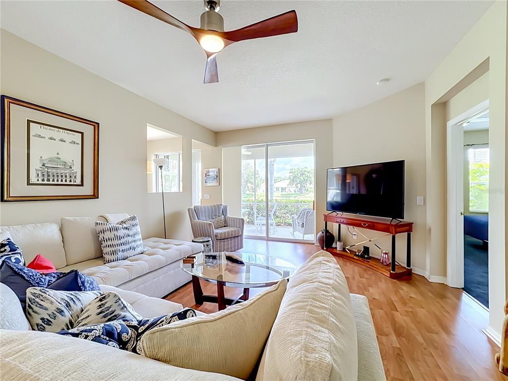 A living room features a sectional sofa, a glass coffee table, and a television console — 4346 KARIBA LAKE TERRACE, SARASOTA, FL