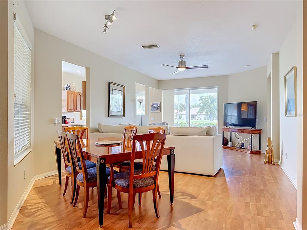 A dining area with a wooden table and chairs opens into a living room with hardwood floors — 4346 KARIBA LAKE TERRACE, SARASOTA, FL