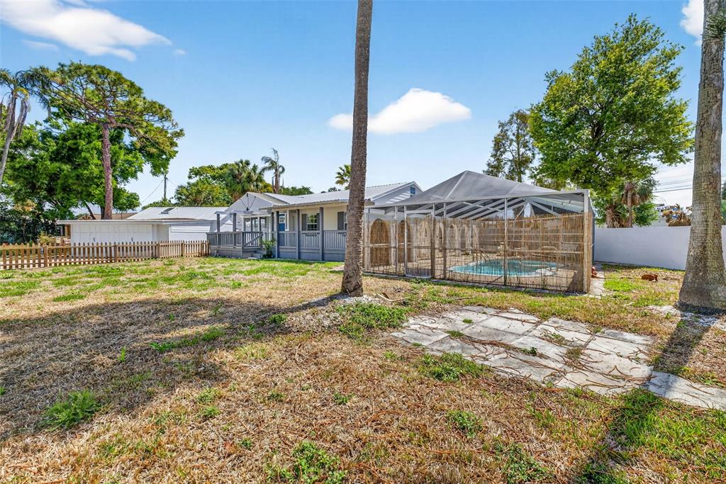 A backyard with a screened-in pool, a wooden deck, and a fenced lawn — 3620 E TAMPA CIRCLE, TAMPA, FL