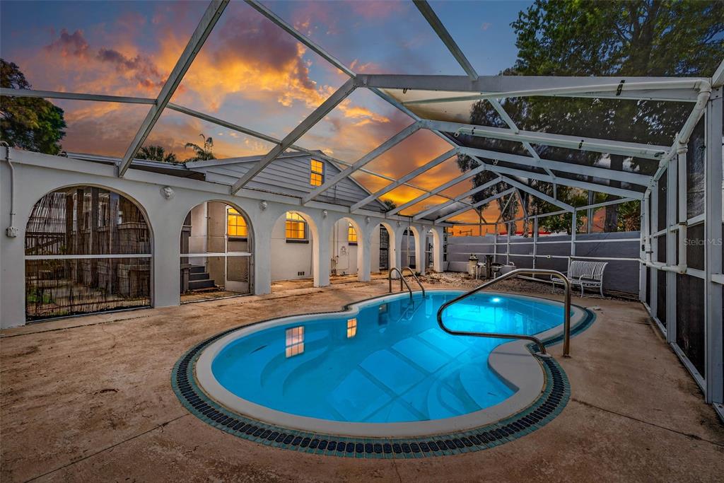 An enclosed swimming pool area with arched doorways and a sunset view in the background — 3620 E TAMPA CIRCLE, TAMPA, FL