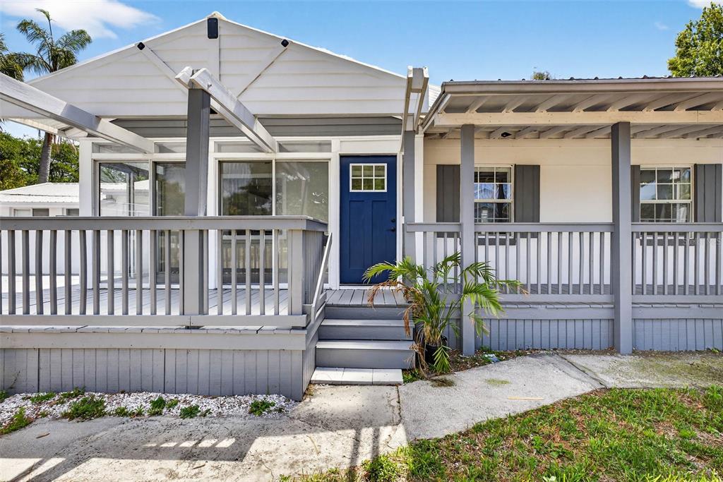 A house exterior features a blue front door, a gray wooden deck, and a porch — 3620 E TAMPA CIRCLE, TAMPA, FL