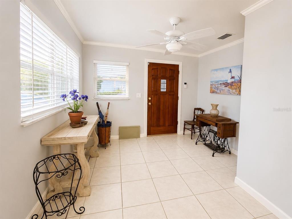 A bright entryway features white tile floors, a wooden front door, and two console tables — 1205 LISA LANE, OKEECHOBEE, FL