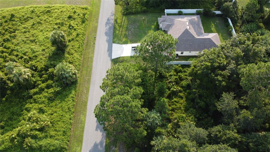 An aerial view shows a house with a driveway next to a road and woods — LOT 12 ATTALLA AVENUE, NORTH PORT, FL