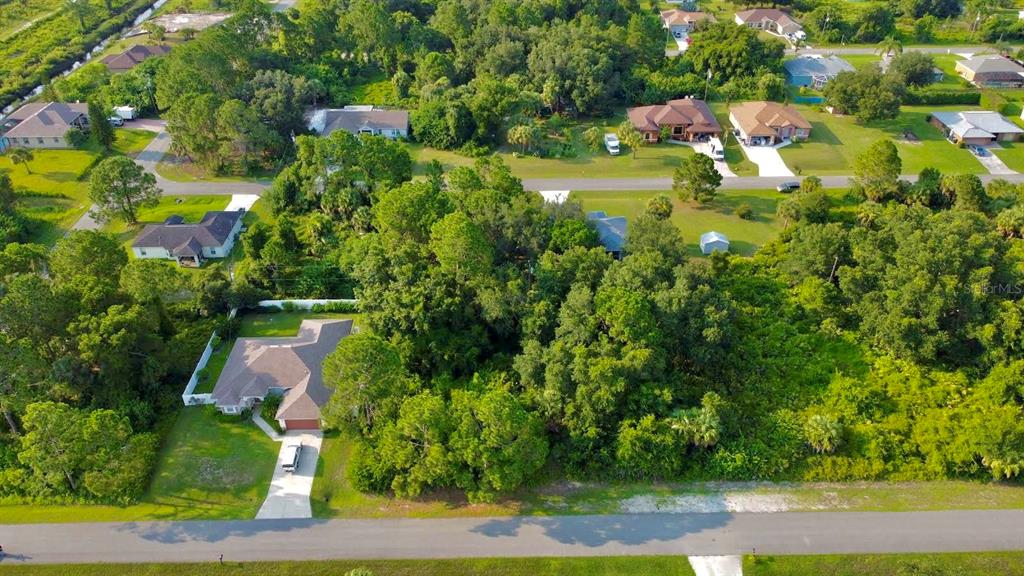 An aerial view shows a residential neighborhood with houses surrounded by dense trees and vegetation — LOT 12 ATTALLA AVENUE, NORTH PORT, FL