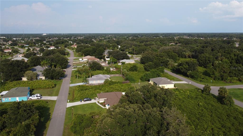 An aerial view shows several single-family homes surrounded by dense trees and paved roads — LOT 12 ATTALLA AVENUE, NORTH PORT, FL