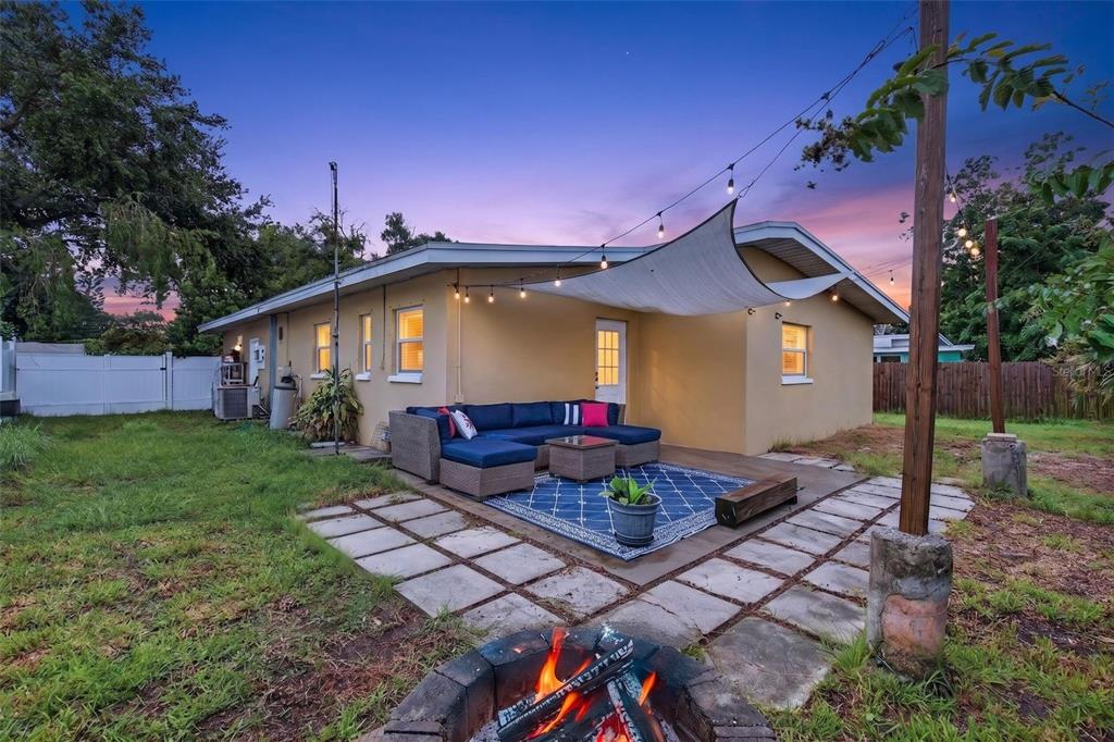 A backyard patio features a blue sectional sofa, a fire pit, and string lights overhead — 12496 136TH LANE, LARGO, FL