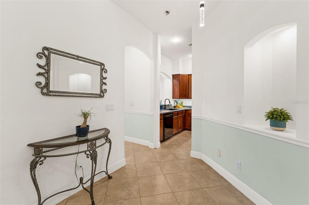 A hallway with tile flooring leads to a kitchen featuring dark wood cabinetry — 8414 MARIA COURT UNIT 5, CAPE CANAVERAL, FL