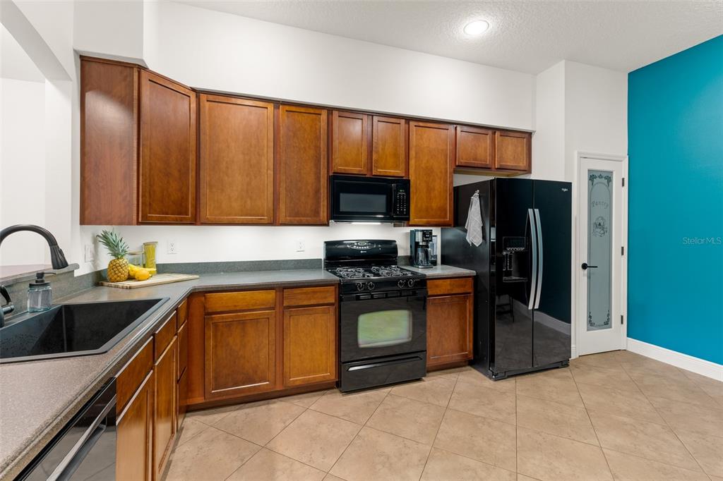 A kitchen features wood cabinets, black appliances, dark countertops, and a teal accent wall — 8414 MARIA COURT UNIT 5, CAPE CANAVERAL, FL