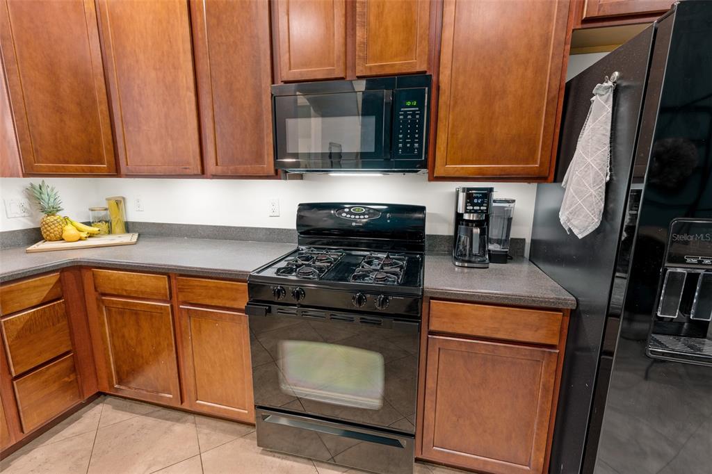 A kitchen features wood cabinets, black appliances, and a gray countertop — 8414 MARIA COURT UNIT 5, CAPE CANAVERAL, FL