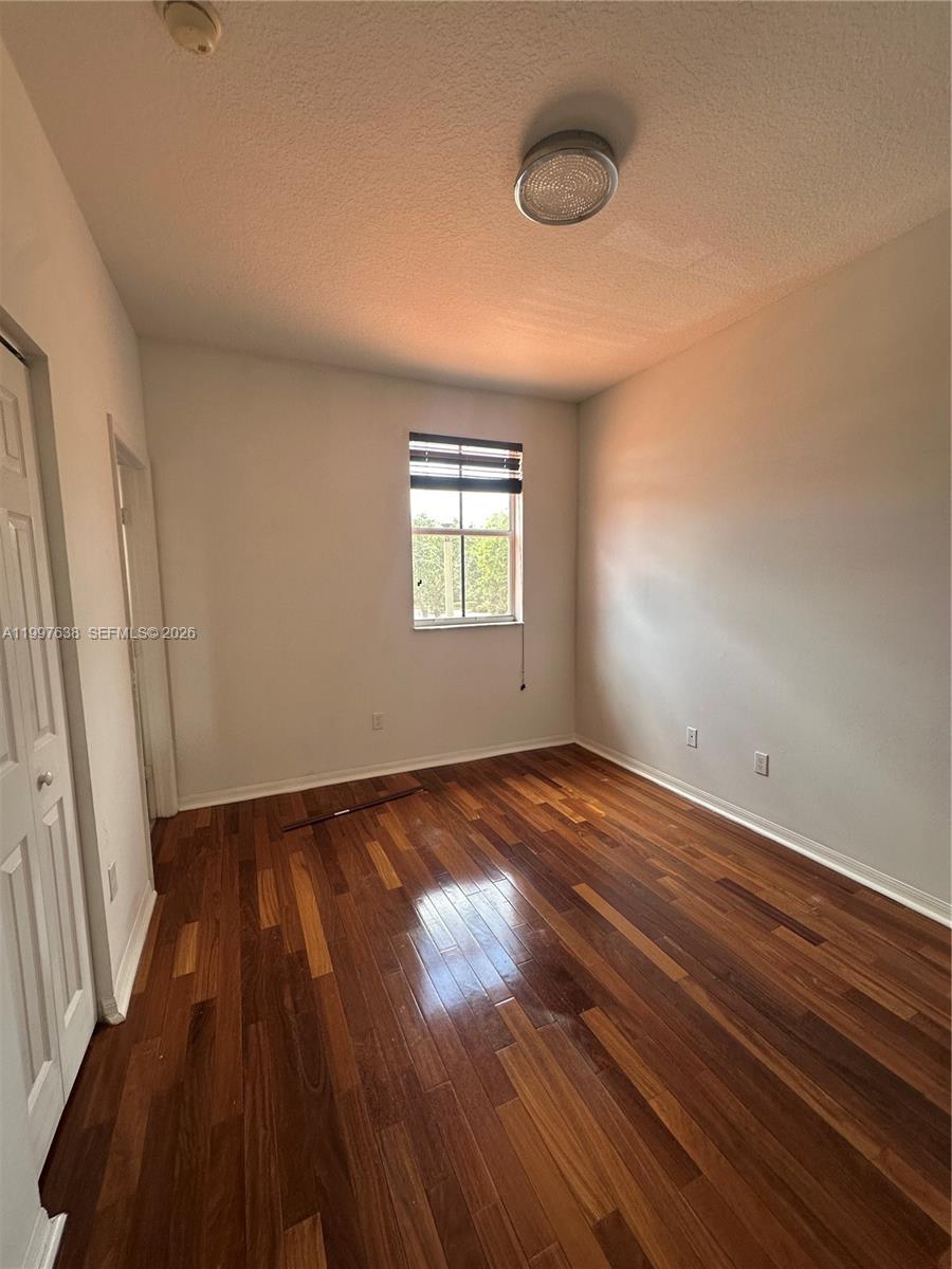 An empty bedroom features hardwood flooring, white walls, and a single window with blinds — 2191 Anchor Ct # 1902, Dania Beach FL 33312, DANIA BEACH, FL