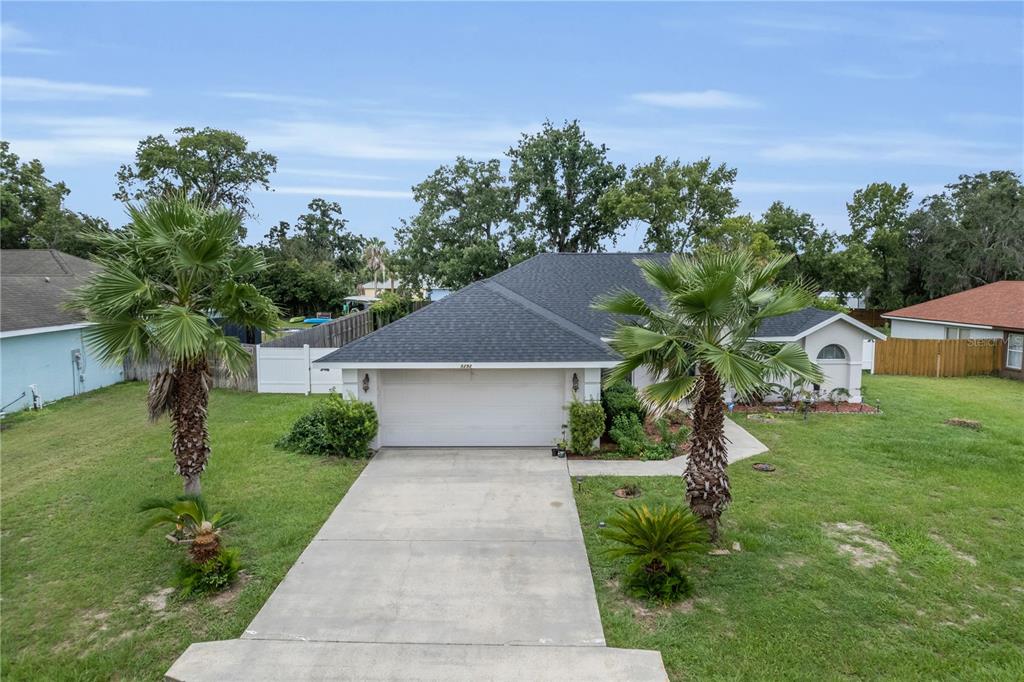 An exterior view of a single-story house with a white garage, driveway, and two palm trees — 5292 SW 115TH LOOP, OCALA, FL