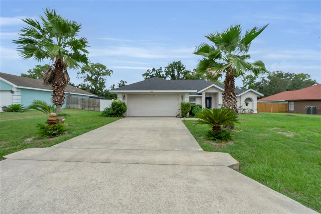A single-story house with a two-car garage, concrete driveway, and two palm trees in front — 5292 SW 115TH LOOP, OCALA, FL