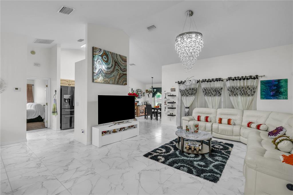 A bright living room features white marble-look tile floors, a white sectional sofa, and a chandelier — 5292 SW 115TH LOOP, OCALA, FL