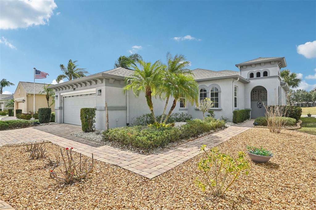 A single-story house with a gray exterior, a two-car garage, and a landscaped front yard — 819 REGAL MANOR WAY, SUN CITY CENTER, FL