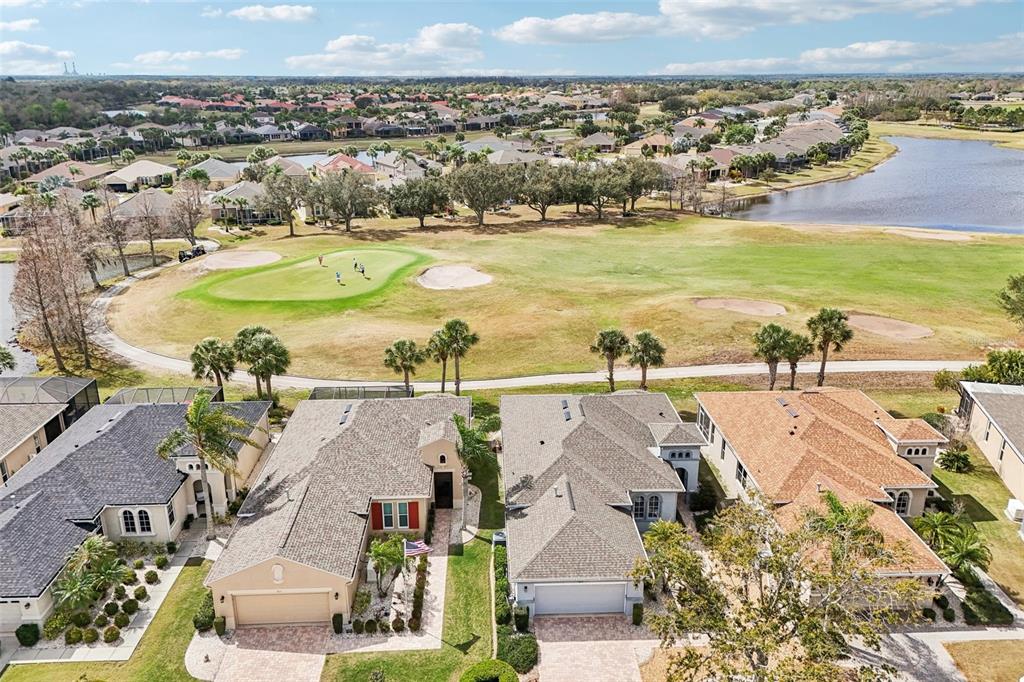 An aerial view shows suburban houses bordering a golf course and a lake — 819 REGAL MANOR WAY, SUN CITY CENTER, FL