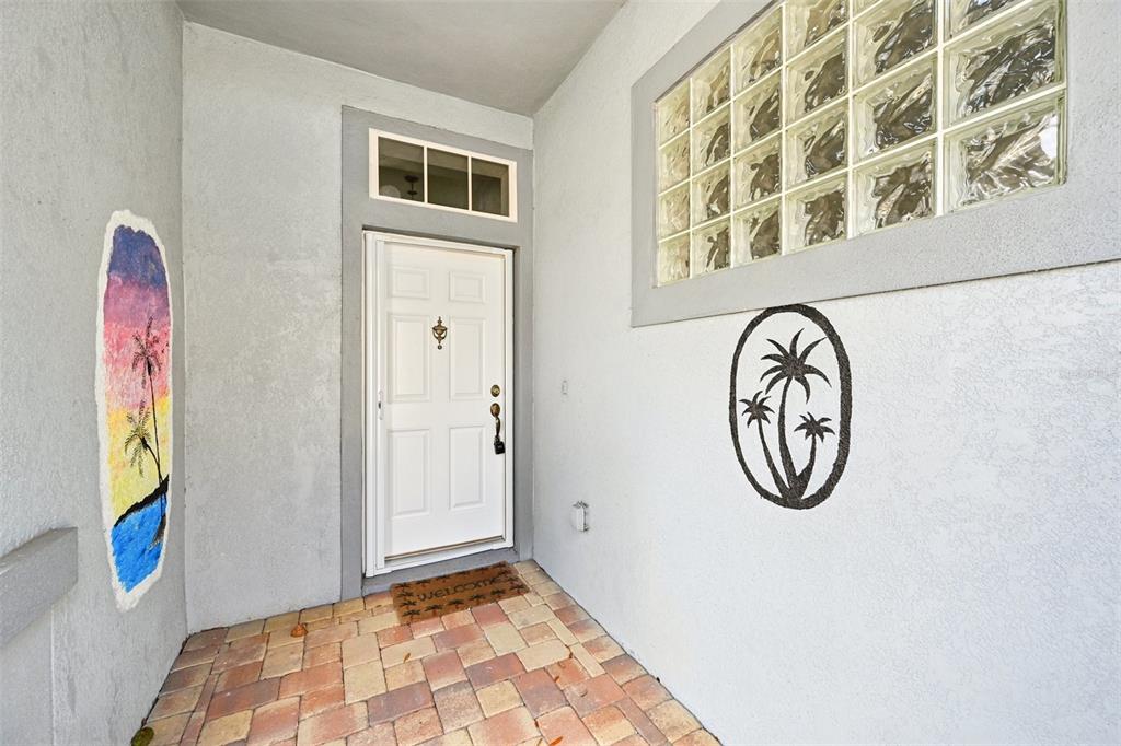 A front entryway features a white door, glass block window, and a paved porch — 819 REGAL MANOR WAY, SUN CITY CENTER, FL