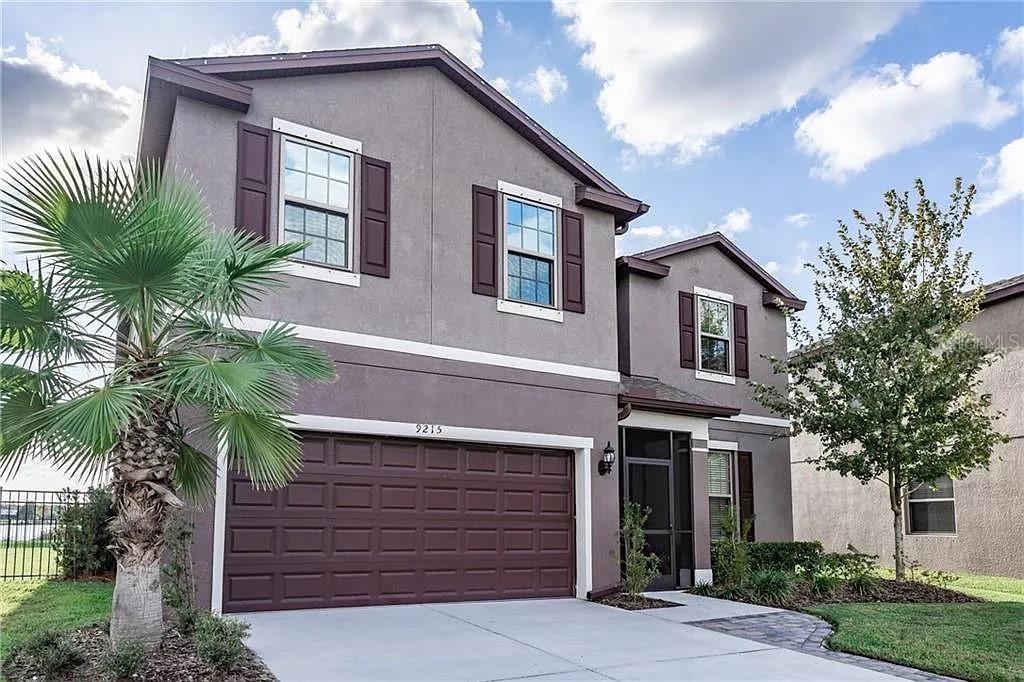 A two-story house with a gray stucco exterior, dark shutters, and a two-car garage — 9215 MOUNTAIN MAGNOLIA DRIVE, RIVERVIEW, FL