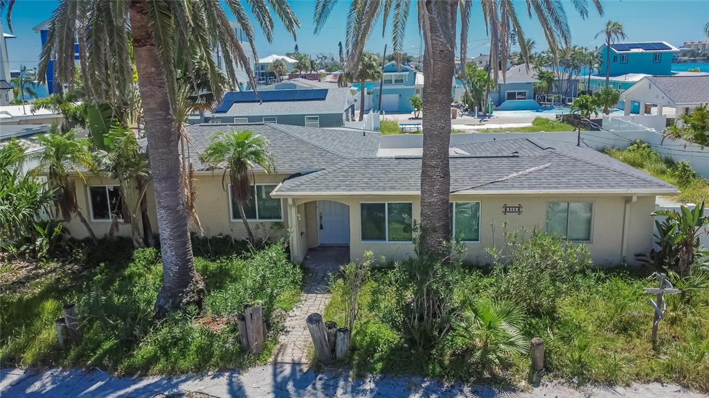 An exterior view of a single-story house with a gray roof and palm trees — 363 145TH AVENUE E, MADEIRA BEACH, FL