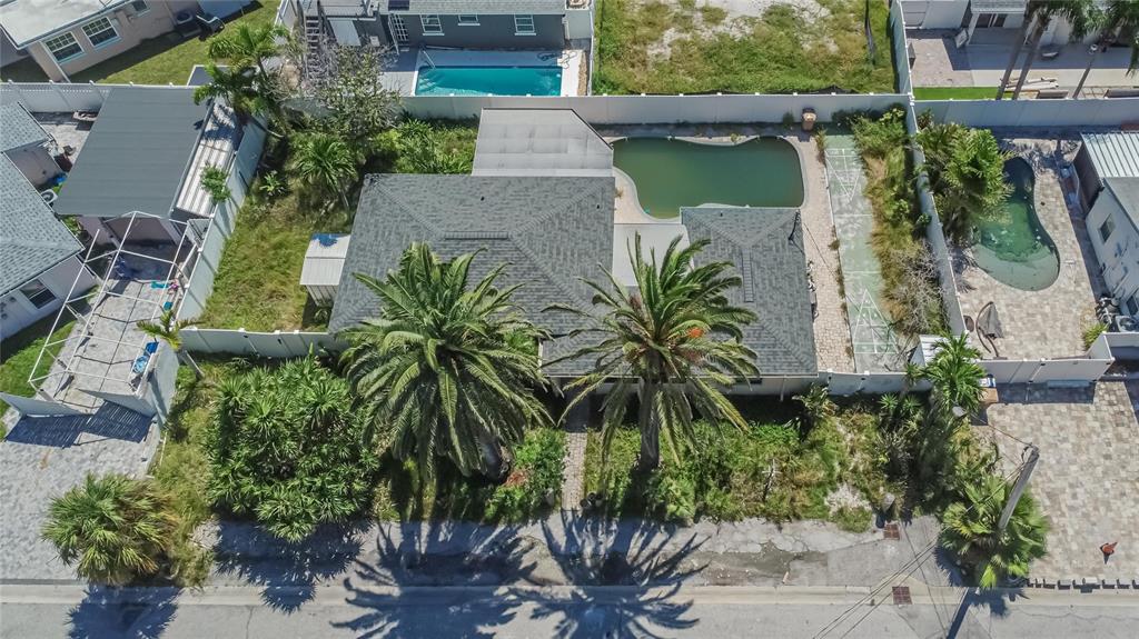 An aerial view shows a house with two palm trees, a pool, and a shuffleboard court — 363 145TH AVENUE E, MADEIRA BEACH, FL