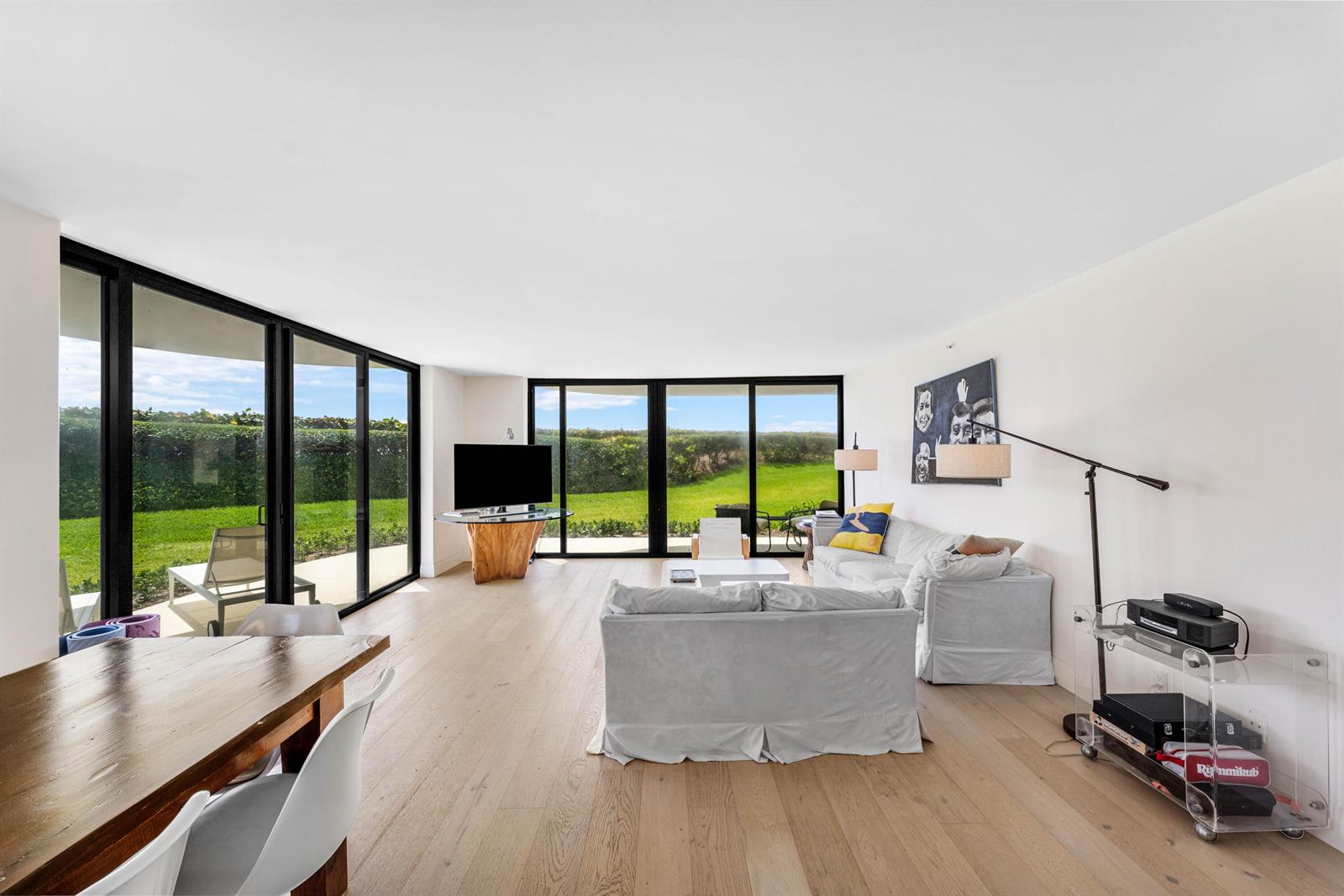 A living room with light wood floors, white sofas, and floor-to-ceiling windows overlooking a lawn — 3360 S Ocean Boulevard # I, Palm Beach FL 33480, PALM BEACH, FL