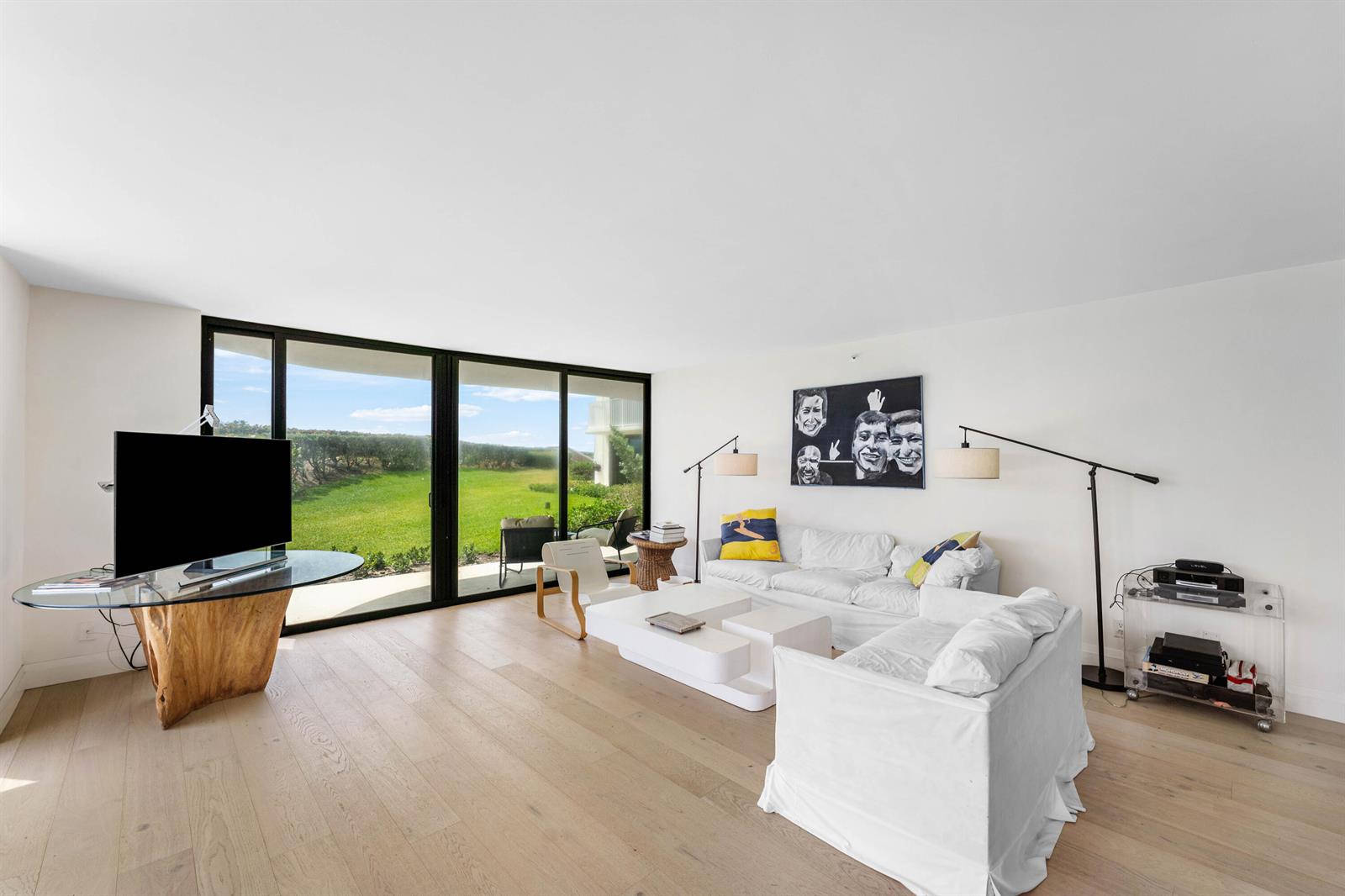 A living room features white sofas, a wooden-base glass TV stand, and large sliding glass doors — 3360 S Ocean Boulevard # I, Palm Beach FL 33480, PALM BEACH, FL