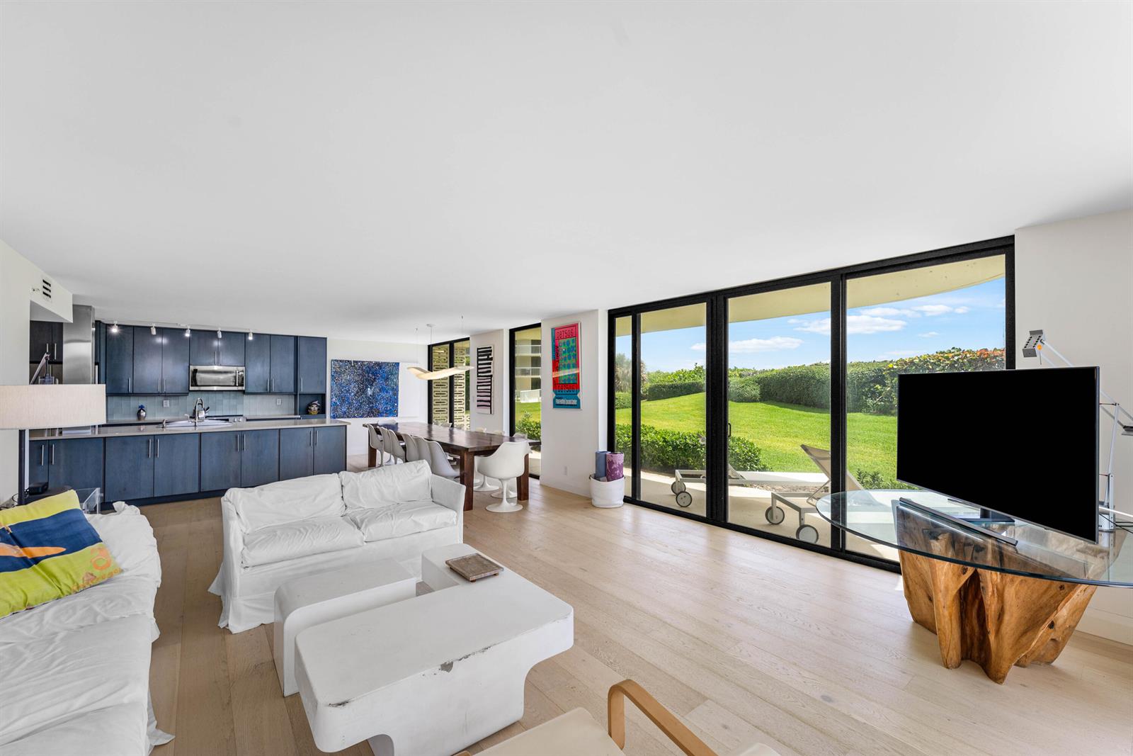 An open-concept living area features a kitchen, dining space, and floor-to-ceiling windows overlooking greenery — 3360 S Ocean Boulevard # I, Palm Beach FL 33480, PALM BEACH, FL