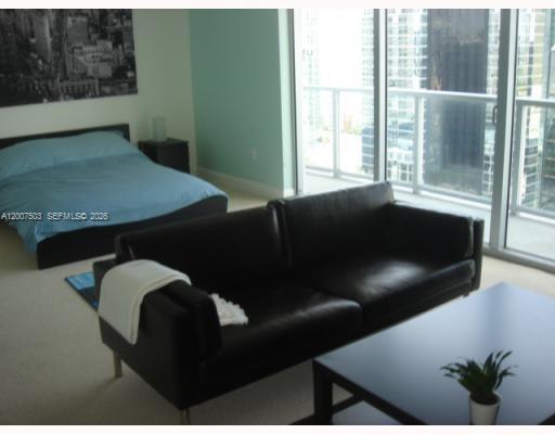 A bedroom with a bed, a black leather sofa, and floor-to-ceiling windows overlooking a city — 1050 Brickell Ave # 2312, Miami FL 33131, MIAMI, FL