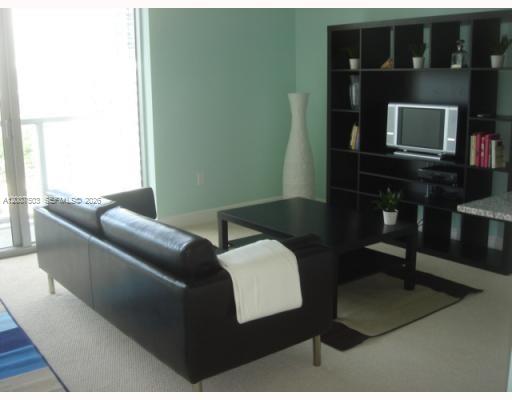 A living room features a black leather sofa, a matching coffee table, and shelving unit — 1050 Brickell Ave # 2312, Miami FL 33131, MIAMI, FL