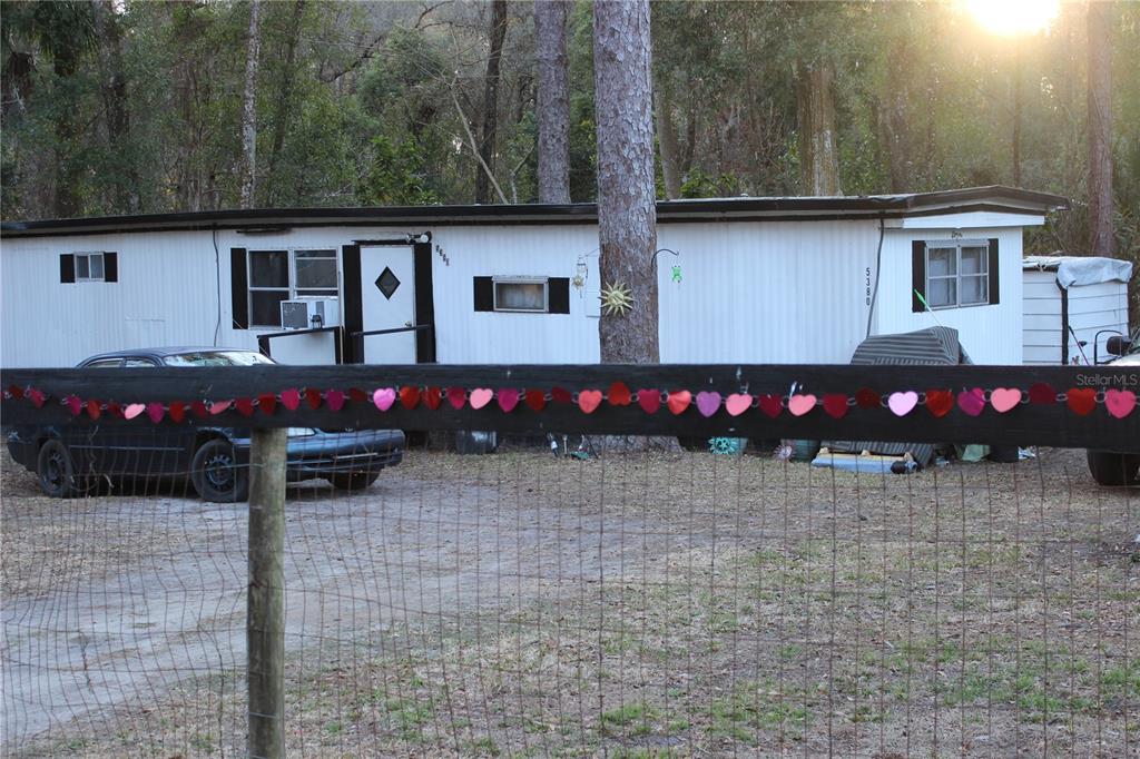 A single-wide mobile home sits behind a wooden fence decorated with a string of hearts — 5380 SE 28TH COURT, OCALA, FL