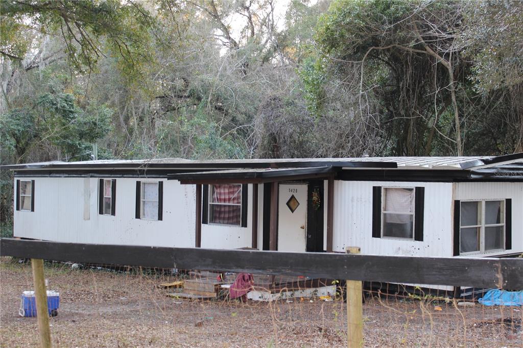 A single-story mobile home with white siding and black trim sits behind a wooden fence — 5380 SE 28TH COURT, OCALA, FL
