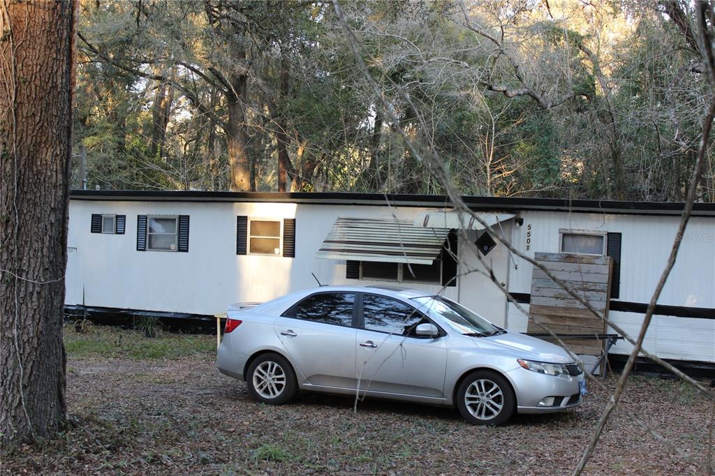 A silver sedan is parked in front of a white mobile home with black shutters — 5380 SE 28TH COURT, OCALA, FL