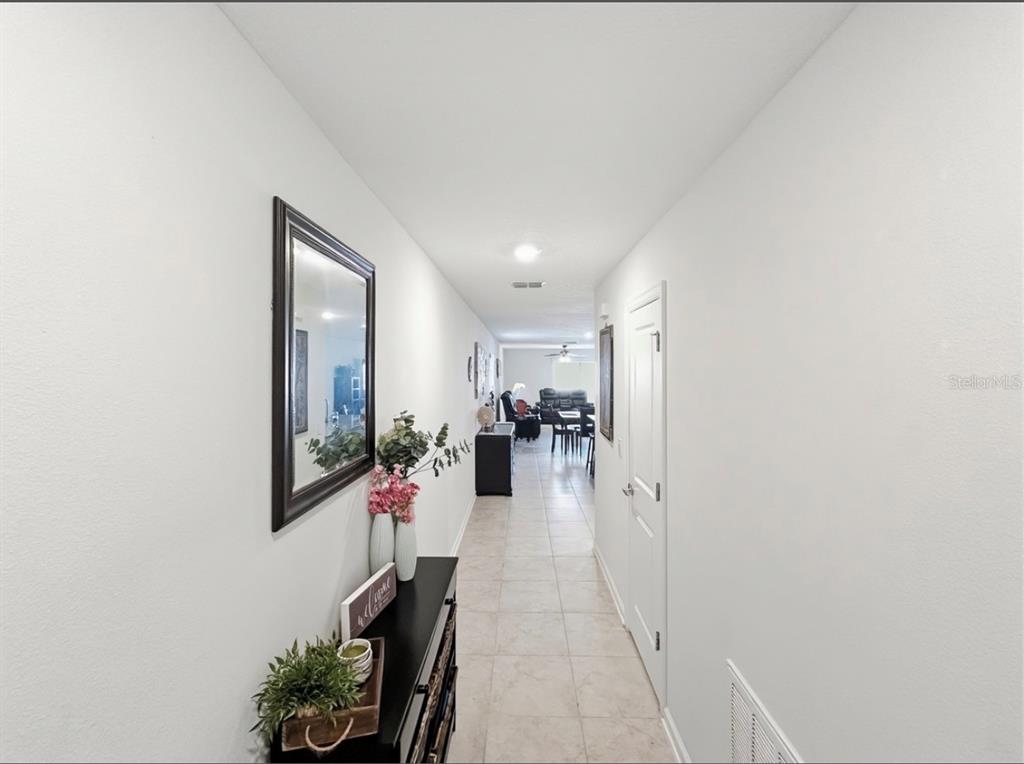 A hallway with tile flooring leads from a console table toward an open living area — 1988 TRAVERSE WAY, KISSIMMEE, FL