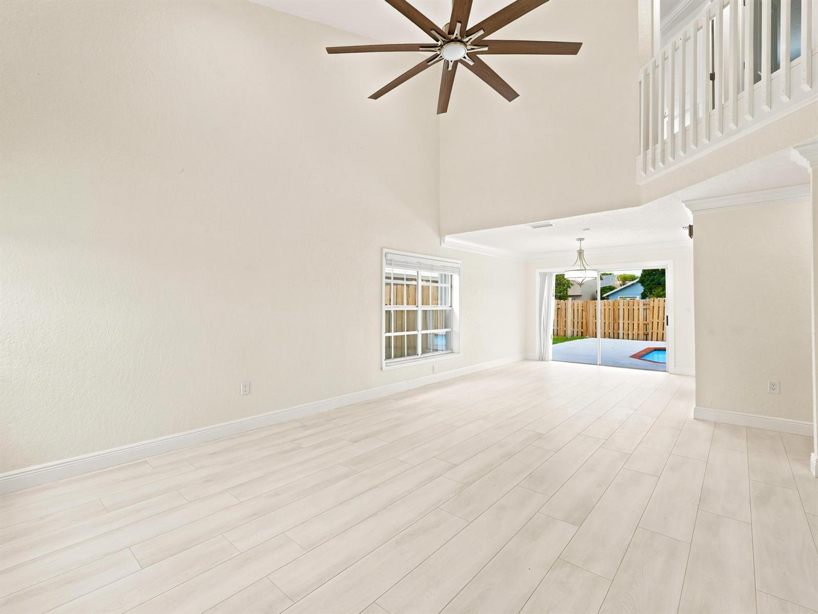 An empty living room with high ceilings, a ceiling fan, light wood flooring, and sliding doors — 3157 NW 120th Way, Sunrise FL 33323, SUNRISE, FL