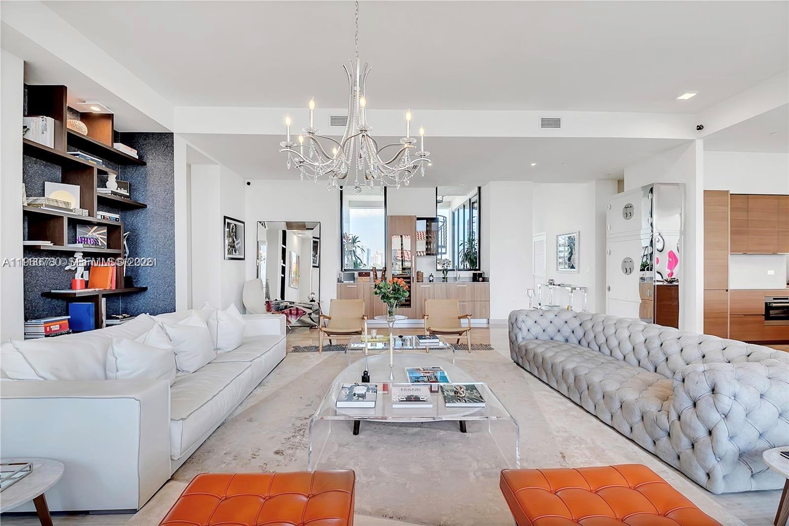 A spacious living room features a crystal chandelier, two large sofas, and built-in shelving — 3581 E Glencoe St # 605, Coconut Grove FL 33133, COCONUT GROVE, FL