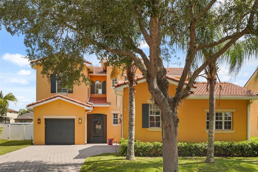A two-story yellow stucco house with a tile roof, a garage, and a paved driveway — 3827 GOLDEN KNOT DRIVE, KISSIMMEE, FL