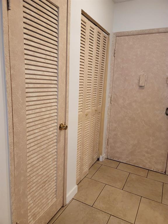 A hallway features beige tile flooring, a louvered closet door, and a solid entry door — 1690 NE 191TH STREET UNIT 315, MIAMI, FL