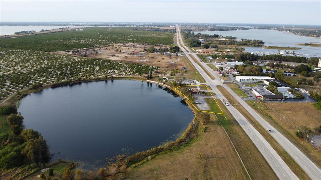 An aerial view shows a lakeside commercial property outlined in yellow next to a highway — 2200 - 2204 US 27 HIGHWAY S, LAKE PLACID, FL