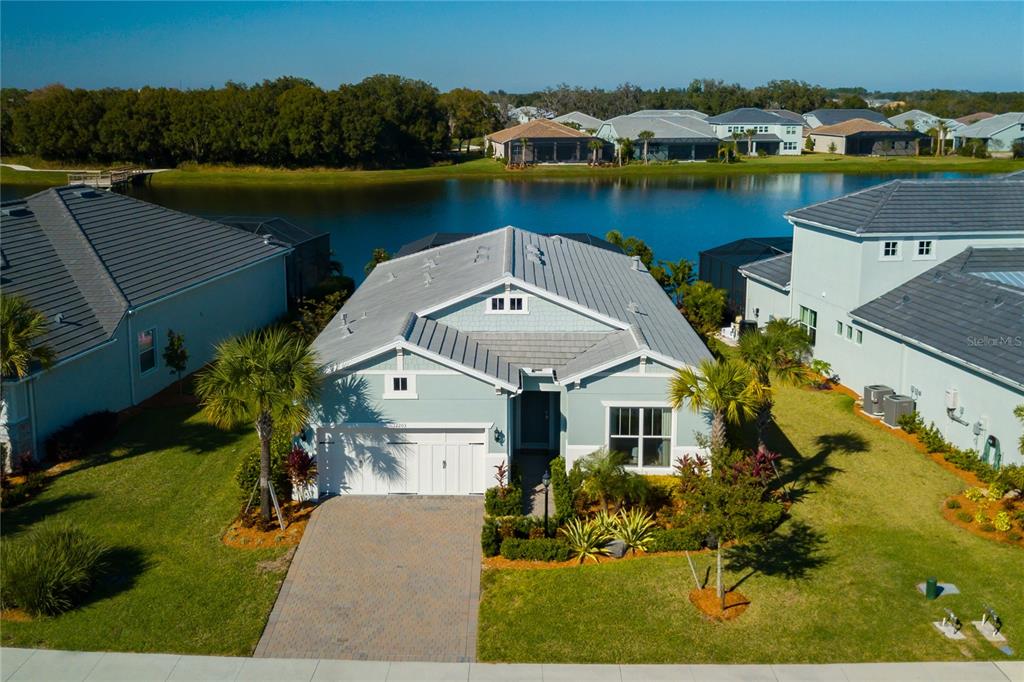 An aerial view of a light blue single-story house with a metal roof and driveway — 12203 SEABROOK AVENUE, BRADENTON, FL