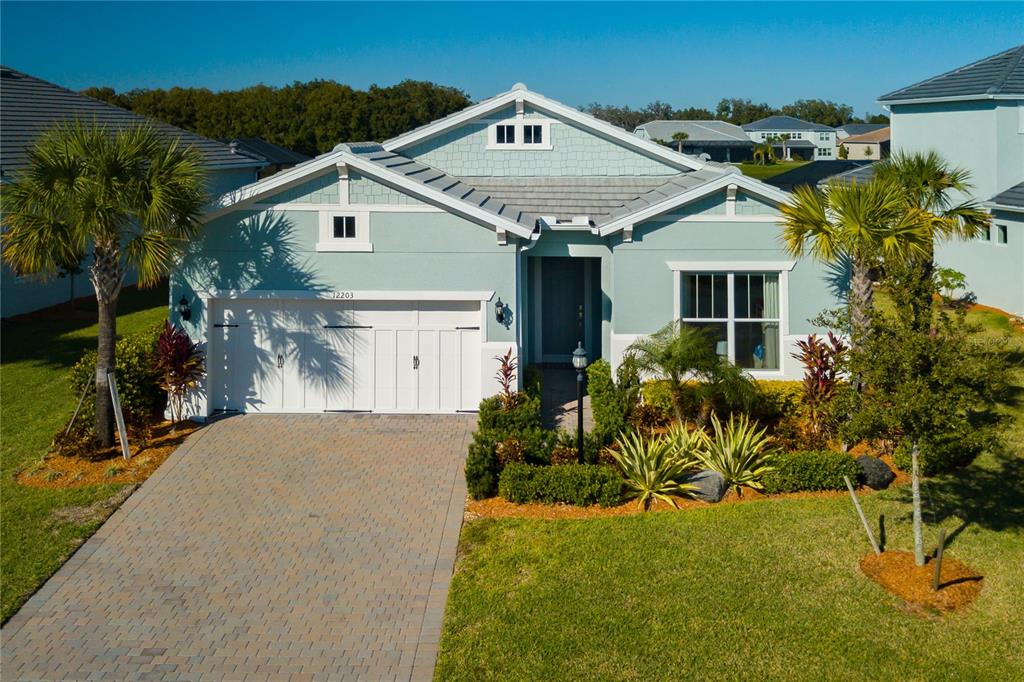 A light blue single-story house with a paved driveway and a two-car garage — 12203 SEABROOK AVENUE, BRADENTON, FL