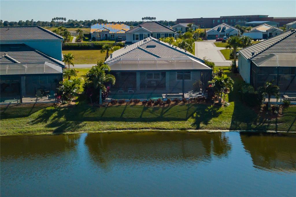 An aerial view of a suburban house with a screened-in pool overlooking a lake — 12203 SEABROOK AVENUE, BRADENTON, FL