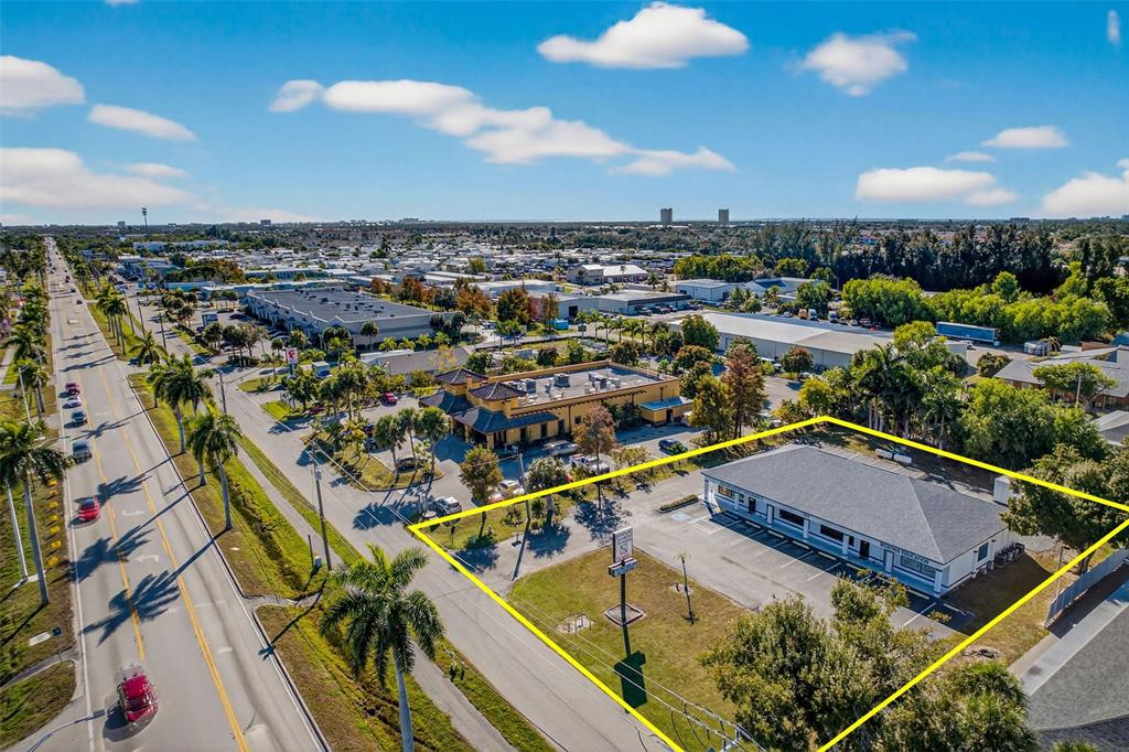 An aerial view shows a commercial building with a parking lot outlined in yellow — 16048 SAN CARLOS BOULEVARD, FORT MYERS, FL