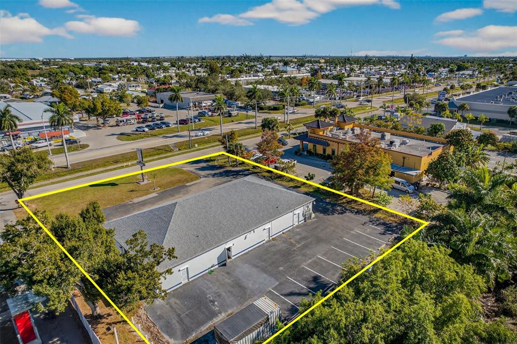 An aerial view shows a commercial building with a parking lot outlined in yellow — 16048 SAN CARLOS BOULEVARD, FORT MYERS, FL
