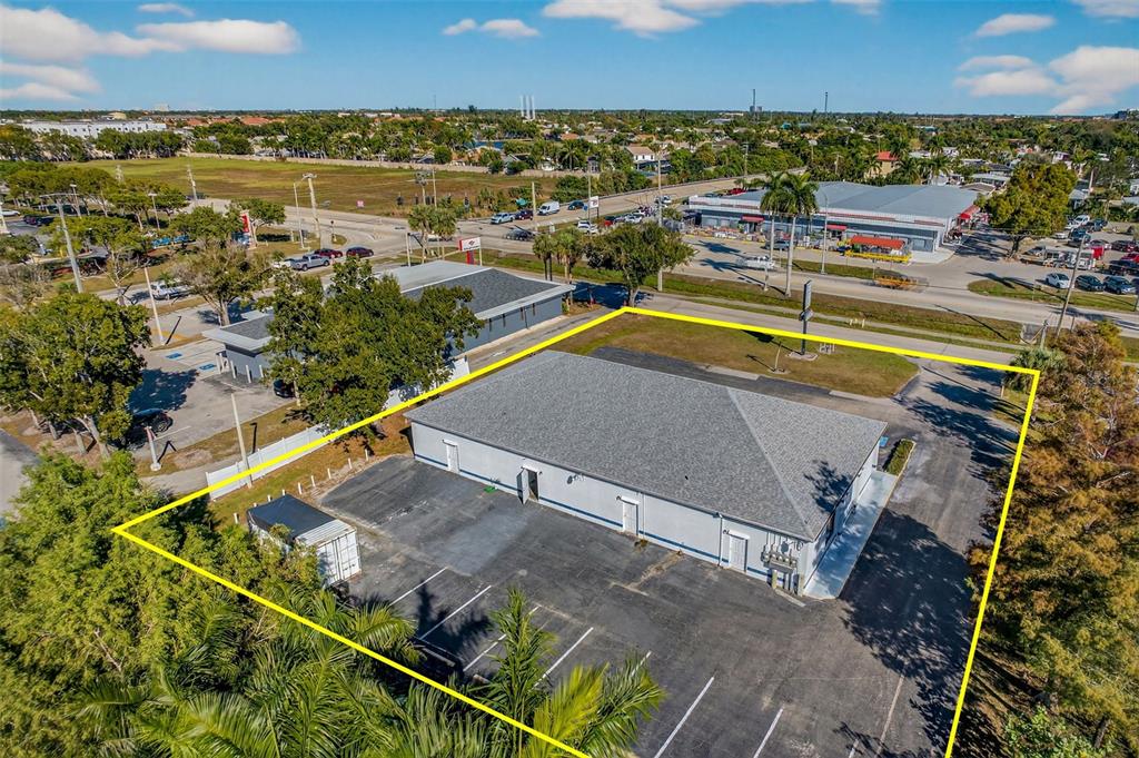 An aerial view shows a commercial building with a gray roof and surrounding parking lot — 16048 SAN CARLOS BOULEVARD, FORT MYERS, FL